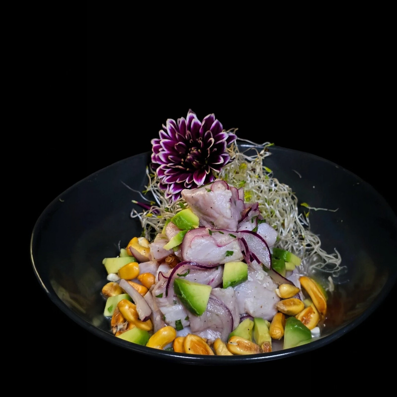 Cubos de pesca blanca y palta, con leche de tigre, cebolla morada, cilantro y maíz cancha.
