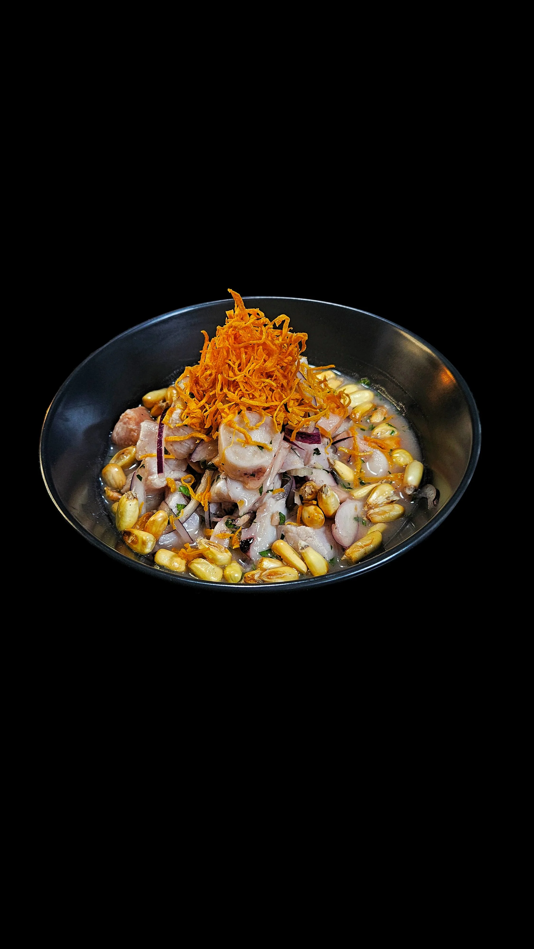 Cubos de salmón, pesca blanca y pulpo, con leche de tigre, cebolla morada, cilantro, salsa de ají picante, chips de boniato y maíz cancha.