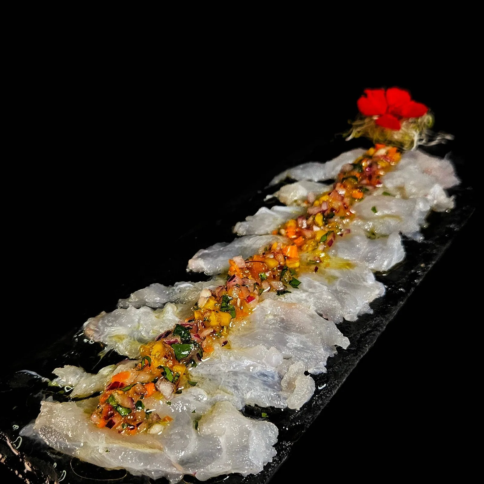 Tiradito de finas láminas de pesca blanca con salsa criolla.