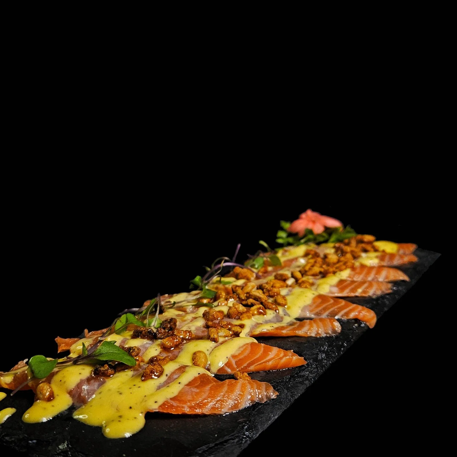Tiradito de finos cortes de salmón con salsa de maracuyá y garrapiñada
